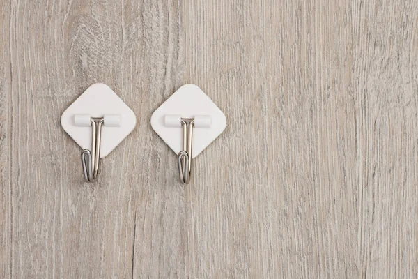 İki plastik yapıştırıcı duvarda asılı elbiseler için metal kancalarla tutturulmuş.