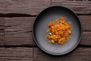 Calendula officinalis - Siyah bir kasedeki organik takvim yaprakları