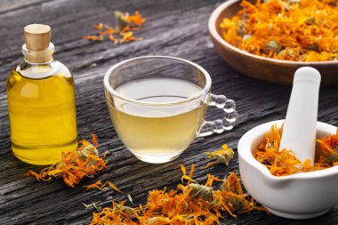 Kurumuş takvim çiçekleri, temel yağ, bir fincan infüzyon ve bir tokmak - Calendula officinalis