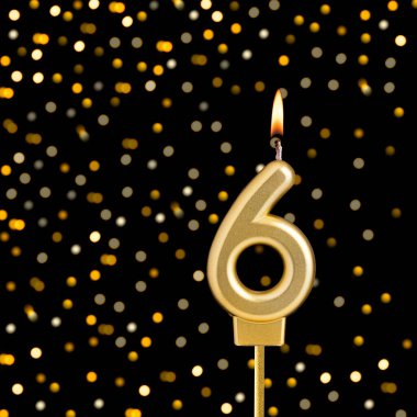 6 numaralı doğum günü mumu, bulanık ışıklarla siyah arka planda.