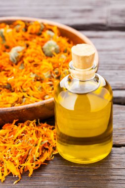 Calendula officinalis - Kırsal ahşap arka planda bir şişe doğal yağ ve kurutulmuş takvim çiçeği