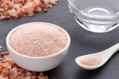 İyi ve kaba Himalaya pembe tuzu kasede ve kaşıkta. Suyla karıştırmak için tuz kristalleri.