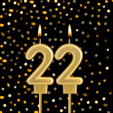 Siyah arka planda 22 numaralı doğum günü mumu bulanık ışıklarla