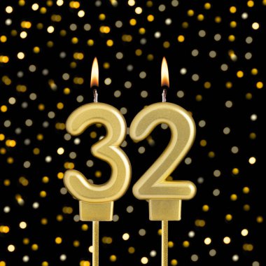 Siyah arkaplanda bulanık ışıklarla 32 numaralı doğum günü mumu.