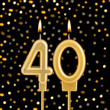 Kırk numaralı doğum günü mumu bulanık ışıklarla siyah arka planda.