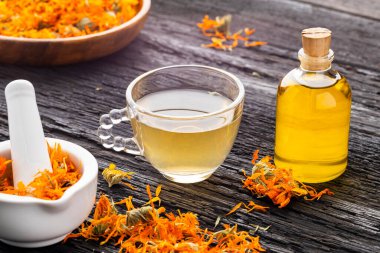 Calendula çayı ve kurutulmuş yapraklar ve doğal malzemelerle birlikte köy masasında gerekli yağ. Calendula officinalis.
