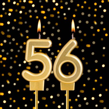 Siyah arka planda, bulanık ışıkları olan 56 numaralı doğum günü mumu.