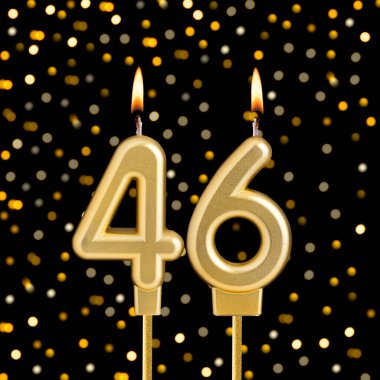 Bulanık ışıklarla siyah arkaplanda 46 numaralı doğum günü mumu.