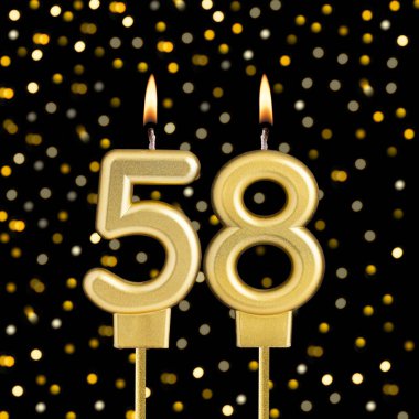 Bulanık ışıklarla siyah arkaplanda 58 numara doğum günü mumu.