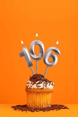 106 numara mum, turuncu arka planda doğum günü kartı tasarımı. Kek.