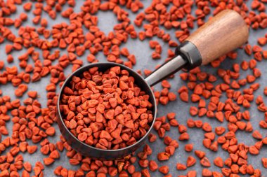 Bixa Orellana - Organik kırmızı notatto tohumları bir ölçü kaşığının üzerinde ve dibe saçılmış
