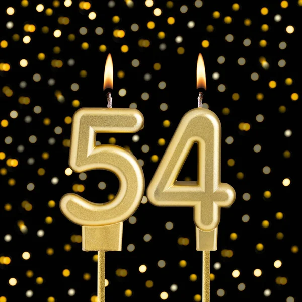Bulanık ışıklarla siyah arkaplanda 54 numara doğum günü mumu.