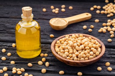 Kırsal ahşap arka planda cam bir şişede soya fasulyesi ve sebze yağı.