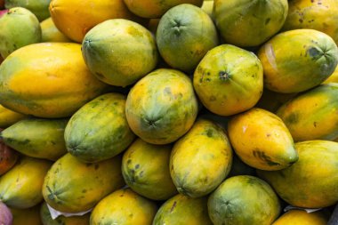 Olgun papayalar Kolombiya pazar meydanında üst üste yığılmış. Bu tropikal meyvenin canlı renklerini ve tazeliğini sergiliyorlar..