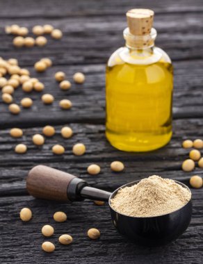 Soya fasulyesi yağı şişesi koyu bir arka planda, sağlıklı beslenme konsepti ve doğal bitkisel yağ ile çevrili..