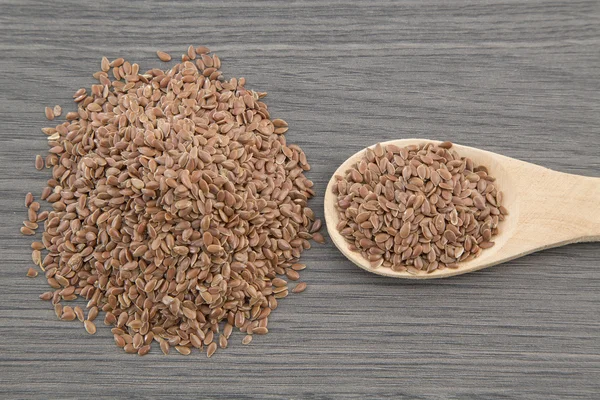 Las semillas de lino se cierran sobre una cuchara de madera sobre una mesa. horizontal — Foto de Stock