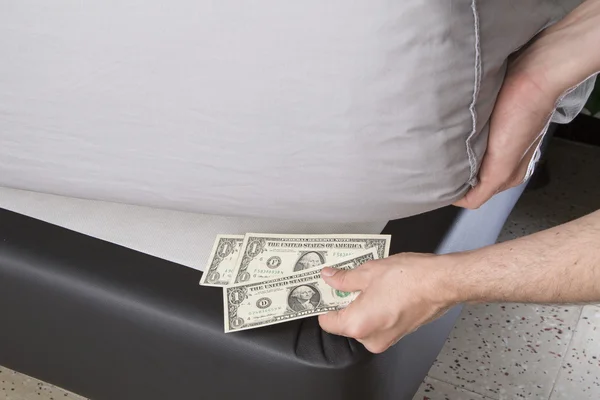 Ruce s penězi je schoval pod matraci — Stock fotografie