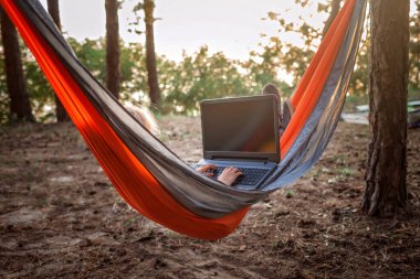 Vahşi ormanlardaki hamakta okuma ve öğrenme için dijital cihaz kullanan sevimli çocuk, çevrimiçi eğitim, yeni normal ve sosyal mesafe yaşam tarzı