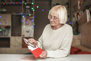 Son sınıf öğrencisi bir zarf tutuyor. Sevgili ailesinden gelen el yapımı Noel tebrik kartı, büyük anne ve babasının bakımı, evdeki sosyal mesafe kutlamaları.