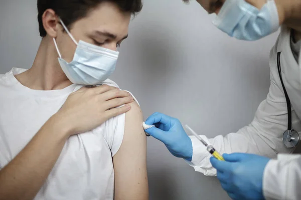 Врач в медицинской маске и перчатках держит ампулу и шприц с коронавирусной вакциной, простудой и гриппом — стоковое фото