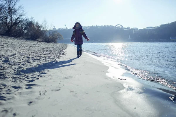 Dziecko spacerujące wzdłuż brzegu rzeki i cieszące się zimą słoneczny dzień, na świeżym powietrzu styl życia — Zdjęcie stockowe