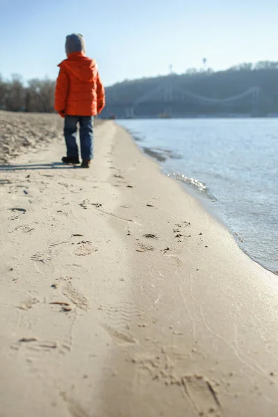 Ребенок идет вдоль берега реки и наслаждается зимним солнечным днем, на открытом воздухе образ жизни — стоковое фото