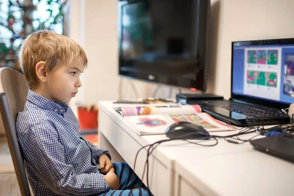 Afstandsonderwijs, online klassenvergadering. Kleuterjongen die thuis tijdens online les studeert — Stockfoto