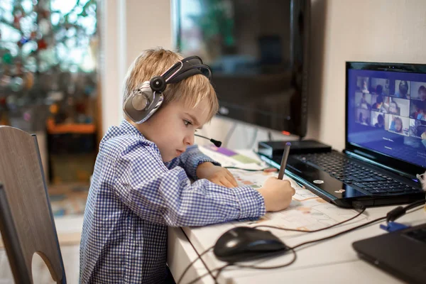 Afstandsonderwijs, online klassenvergadering. Kleuterjongen die thuis tijdens online les studeert — Stockfoto