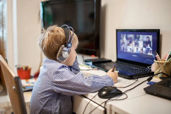 Afstandsonderwijs, online klassenvergadering. Kleuterjongen die thuis tijdens online les studeert — Stockfoto