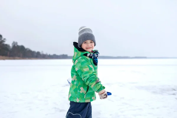 Muchacho quitando nieve del hielo en el lago congelado, invierno, silencio y naturaleza salvaje, estilo de vida —  Fotos de Stock