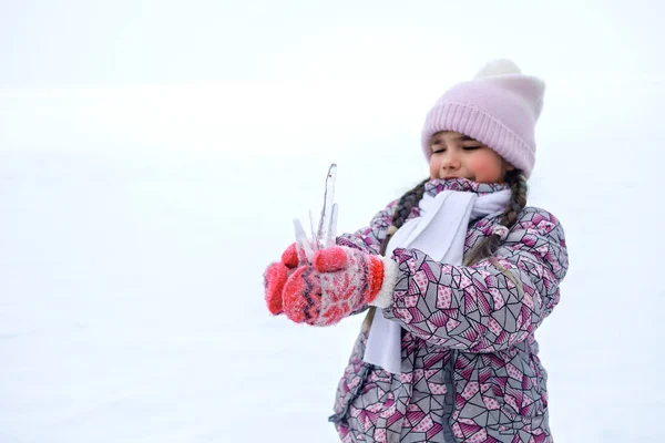 Girl gathering a winter bunch of icicles and taste them, seasonal outdoor activities, lifestyle
