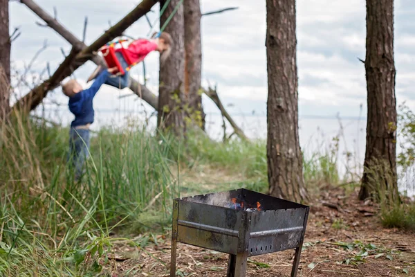 Family outdoor recreation. Kids having fun while parent cooking cheese and sausages by fire