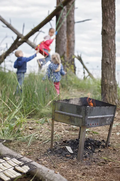 Family outdoor recreation. Kids having fun while parent cooking cheese and sausages by fire