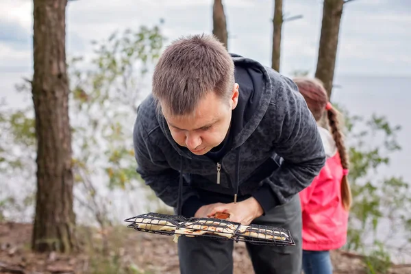 Сімейний відпочинок на свіжому повітрі. Діти розважаються, коли батько готує сир та сосиски вогнем — стокове фото