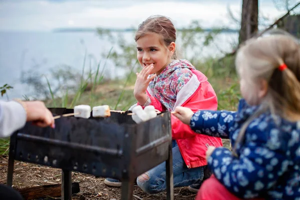 New normal escape step, wild nature walking and family outdoor recreation. Kids standing by the fire and cooking marshmallows, hike at weekend, lifestyle