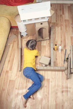 Sıfır atık ev aktivitesi Çocuklar online teslimattan sonra karton kutuyla kağıt ev yapıyorlar ve birlikte oynuyorlar. Ev izolasyonu için yaratıcı bir fikir. Hayal gücü ve yaratıcı düşünce konsepti