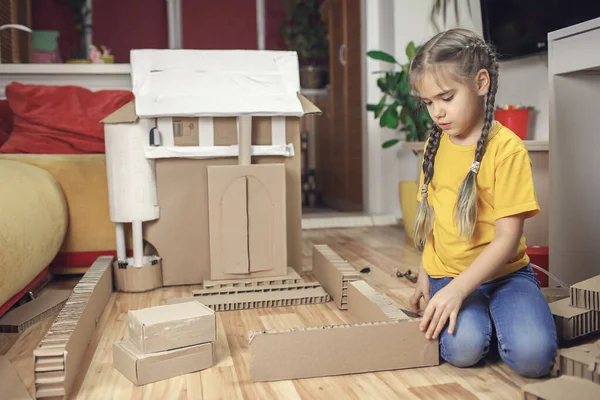 Zero waste home activity. Kids doing paper house with cardboard box after online delivery and playing together, creative idea for home isolation. Imagination skills and creatively thinking concept