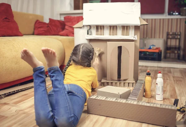 Zero waste home activity. Kids doing paper house with cardboard box after online delivery and playing together, creative idea for home isolation. Imagination skills and creatively thinking concept