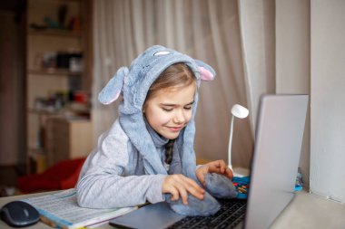 Uzaktan eğitim, online sınıf toplantısı. Evde sıkıcı çevrimiçi dersler sırasında sınıf arkadaşlarını eğlendirmek için komik tavşan şapkası takan güzel bir kız. Karantina sırasında sosyal mesafe, kendini izole etme.