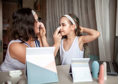 Kız ve annesi internet tabletleriyle güzellik dersi izliyor ve evde spa ameliyatı yapıyorlar.