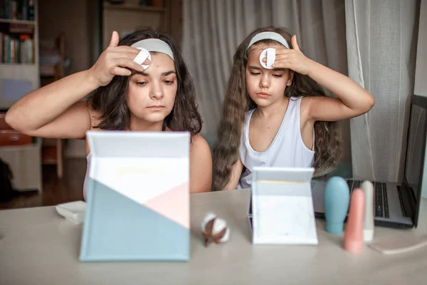 Девочка и ее мама смотрят мастер-класс красоты с таблетками онлайн и делают спа-процедуры дома — стоковое фото