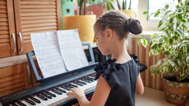 Güzel kız blogcu klasik dijital piyano çalıyor ve evdeki online konser gibi video kaydediyor.