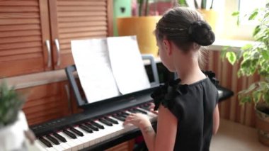 Aile konserinde klasik dijital piyano çalan kız, arka plan, başlangıçta gülümseme.