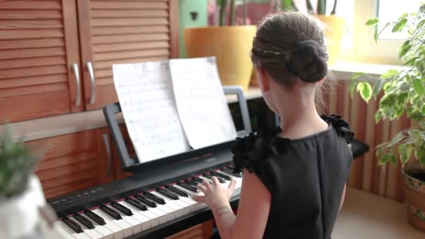 Chica bonita tocando el piano digital clásico durante el concierto en casa de la familia, vista trasera, sonrisa al final — Vídeos de Stock