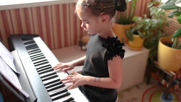 Дівчина грає на класичному цифровому піаніно під час сімейного домашнього концерту, емоційна гра, вид збоку — стокове відео