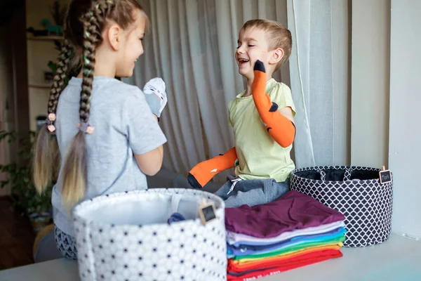 Kinderen reinigen de kamer, sorteren sokken en rangschikken ze in persoonlijke manden. Dagelijkse routine met plezier — Stockfoto