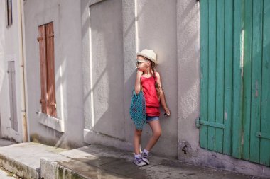 Eski kasabanın caddesinde durmuş yerel dalgıçlarla tatili uzatan, ağ çantalı şık bir kız.