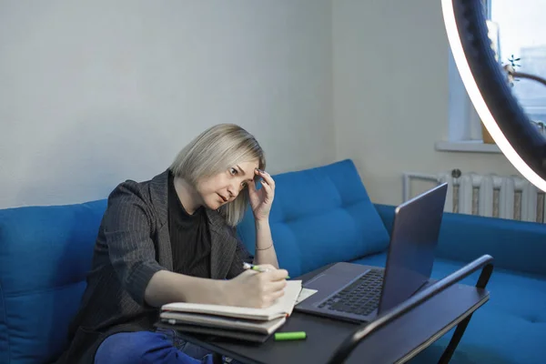 Woman tired from endless video conferences during distant working at home, laptop and ring light