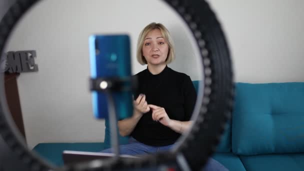 Vrouw in gesprek met camera en opname video met smartphone en ring lamp thuis, vlogger — Stockvideo