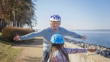 Kız, büyükannesiyle birlikte parkta paten kayıyor. Baharda açık havada.